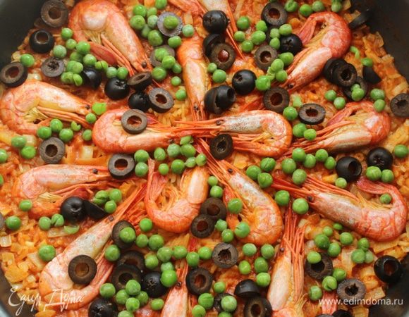 Через 10 минут выложить на рис с креветками горошек и колечки маслин. Снова накрыть крышкой, увеличить огонь до максимума на 1 минуту. Затем огонь убрать и оставить паэлью на 10-15 минут под крышкой.