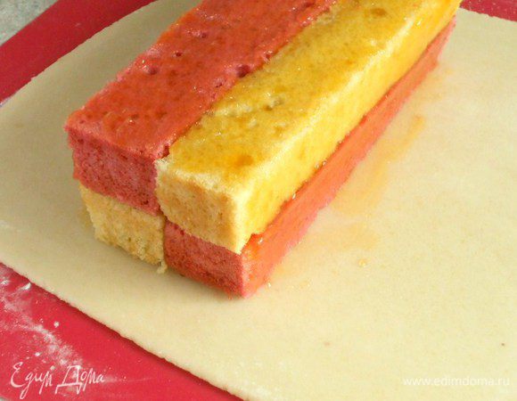 Смажьте верхнюю сторону кекса джемом, переверните её вниз и положите на марципан, ближе к краю. Смажьте  джемом остальные поверхности.. 