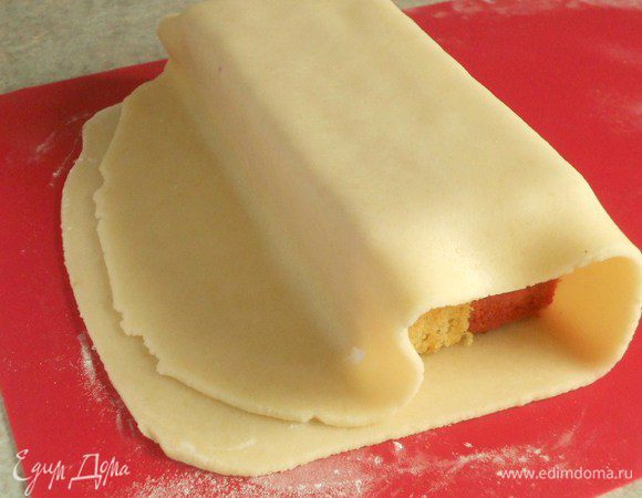 Оберните марципановый пласт вокруг кекса, осторожно прижимая со всех сторон. Соедините края по всей длине.