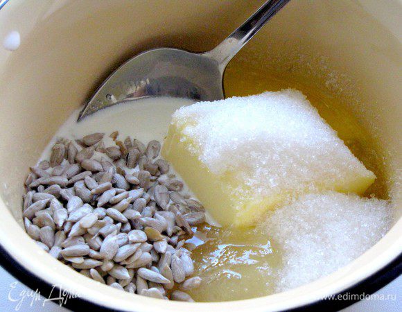 Приготовить заливку. Для этого смешать сахар, мед, сливки, масло и семечки.
