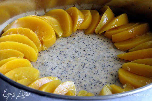 Вынуть пирог из духовки (духовку не выключать). Распределить дольки персиков по кругу в нахлест.
