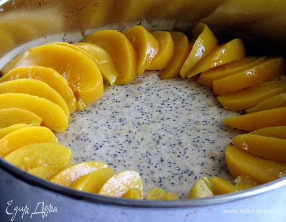 Вынуть пирог из духовки (духовку не выключать). Распределить дольки персиков по кругу в нахлест.