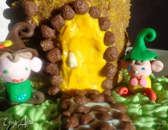 Смазать основу домика коричневым кремом, обсыпать его желтой присыпкой и охладить. Затем аккуратно ножиком нарисовать дверь и окно, выскоблить коричневый крем и заполнить поверхности желтым кремом. По краю положить кукурузные шарики. На двери сделать ручку.