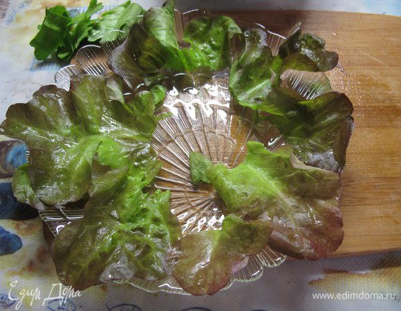 На тарелку выкладываем листья салата. Вынимаем из бульона курицу, даем ей остыть и нарезаем тонкими ломтиками.