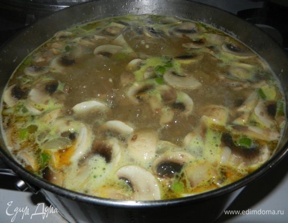 Открыть крышку, добавить промытую перловую крупу и порезанные грибы. Варить 45 минут, пока мясо не станет мягким и перловка будет готова.