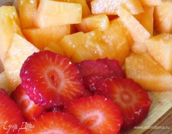 Нарезать кубиками мякоть дыни. Клубнику нарезать тонкими пластинками.Крупно порубить фисташки.