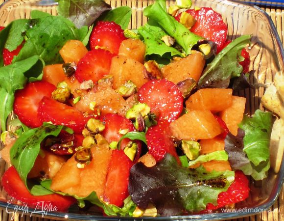 Выложить на блюдо листья салата,клубнику,дыню,посыпать фисташками и заправить.Приятного аппетита:)