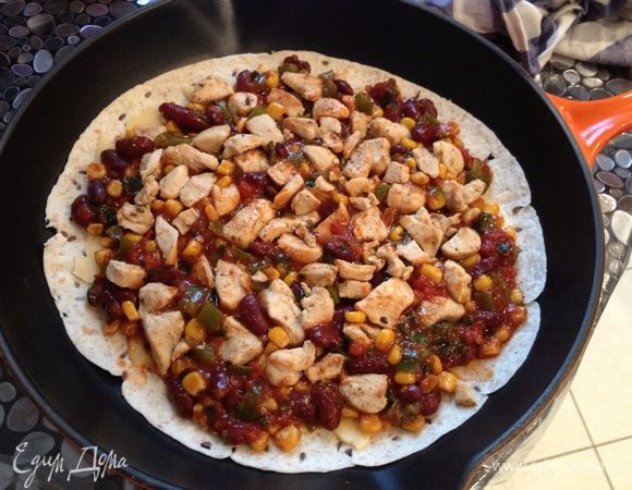 В сухую чугунную сковороду положить тортилью, посыпать тертый сыр, положить овощи, курицу, еще сыр сверху, накрыть второй ленешкой, чуть придавить. В разогретую духовку на 8-10 минут при 170 градусах.