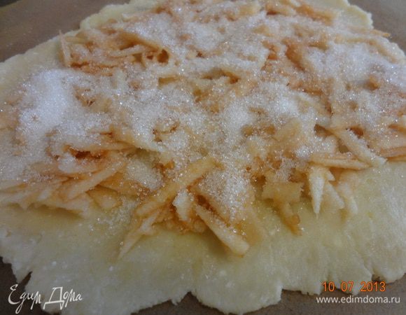 Яблоко очистить от кожуры, удалить сердцевину и натереть на крупной терке, можно нарезать мелкой соломкой, сразу выложить на пласт теста и посыпать сахаром.