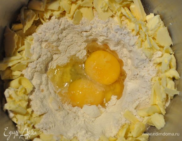 Займёмся тестом. Здесь всё просто, особенно для любителей тартов. В чашу блендера просеять муку и сахарную пудру.
В середину поместить яйцо, желток и соль, по краям - нарезанное кусочками масло. С помощью насадки для теста эта масса быстро превратится в шар.