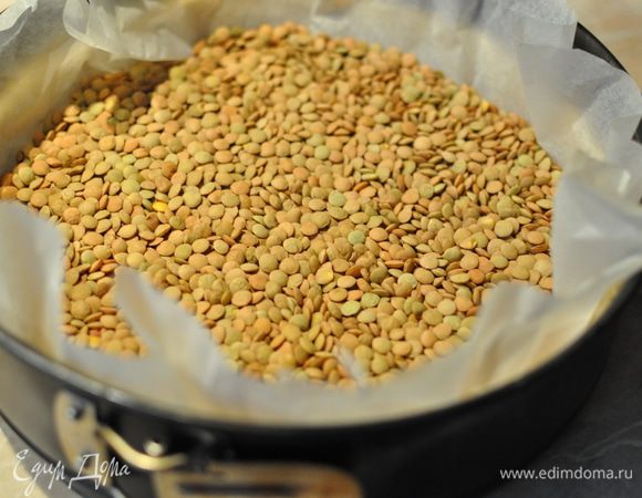 Духовку разогреть до 200 С. Здесь я рекомендую индивидуальный подход. Например у меня при такой температуре всё горит, поэтому для своей выпечки я выбираю температуру 180 С (или №4 для "счастливых" обладательниц газовых духовок отечественного производства).
Тесто застелить бумагой для выпечки и насыпать "утяжелитель" (в моем случае - чечевица). Поставить форму в разогретую духовку на 15 минут.