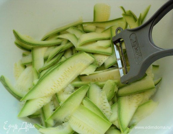 Молодой кабачок разрезать пополам и при помощи овощечистки нарезать тонкими ленточками. 