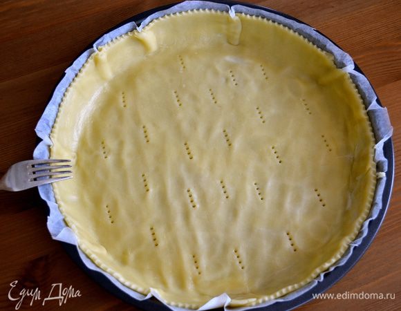 Духовку разогрейте до 180°C. По истечении указанного времени достаньте тесто из холодильника. Раскатайте в тонкий пласт и выложите в форму для открытых пирогов. Проткните тесто по всей площади вилкой.