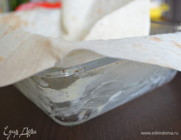 Стеклянную форму 25х20 см смазать сливочным маслом и уложить целиком в нее 1 лист лаваша так, чтобы края свисали.