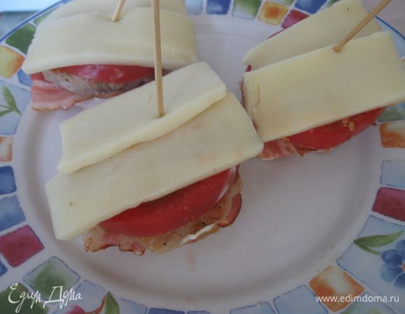  На помидор выложить тонкие кусочки сыра.  Скрепить «пирамидку» деревянной шпажкой. Форму  застелить пергаментной бумагой. Духовку разогреть до 200 градусов. Запечь в  духовке  до появления румяной корочки у сыра.
