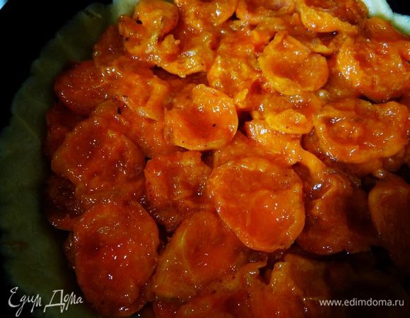 Одну часть уложить в противень, сформировать высокие бортики. Сверху выложить абрикосы. 