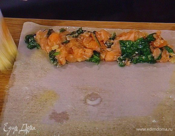 Листок теста  выложить на рабочую поверхность,смазать водой, смешанной с белком.  Начинку выложить полосочкой, отступив с краю несколько мм.