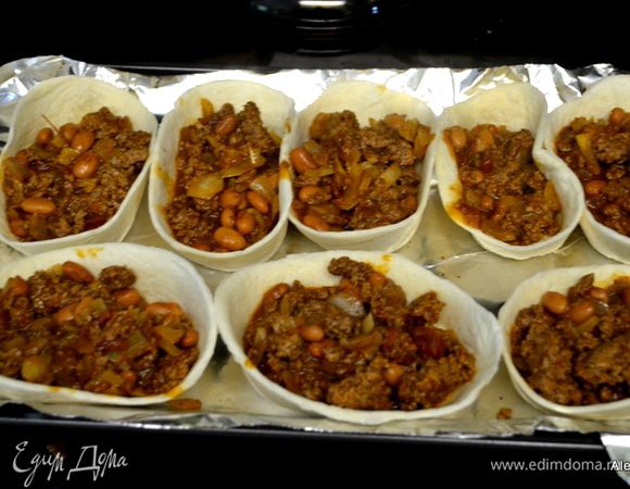На противень выложить лист фольги. Разложить корзиночки или ракушки Тако. Выложить мясную смесь с фасолью поверх каждой корзиночки.