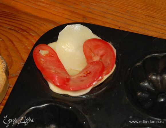 Формочки с антипригарным покрытием смазываем маслом и начинаем укладывать в них сначала картофель, затем помидоры