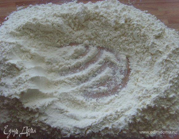 Муку высыпать горкой на рабочую поверхность, внутри горки сделать  углубление.