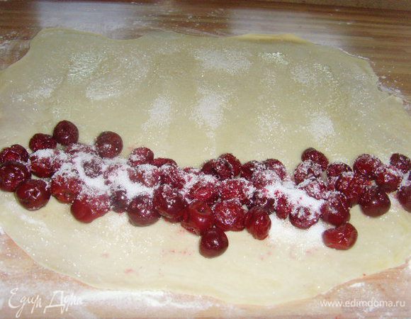 Рабочую поверхность присыпать мукой. Тесто раскатать тоненько  прямоугольником. Лист теста слегка смазать растительным маслом и слегка  посыпать сахаром. С длинного края выложить вишню в ряд, присыпать сахаром (если вы помните, в тесте у меня отсутствует сахар, поэтому количество сахара кладите по своему вкусу и в зависимости от кислоты вишни).