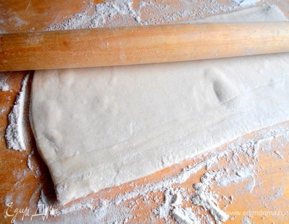 Тесто заранее вынимаем из морозилки и раскатываем один пласт ( у меня в пачке два пласта по 250 г ), припорошив доску мукой.