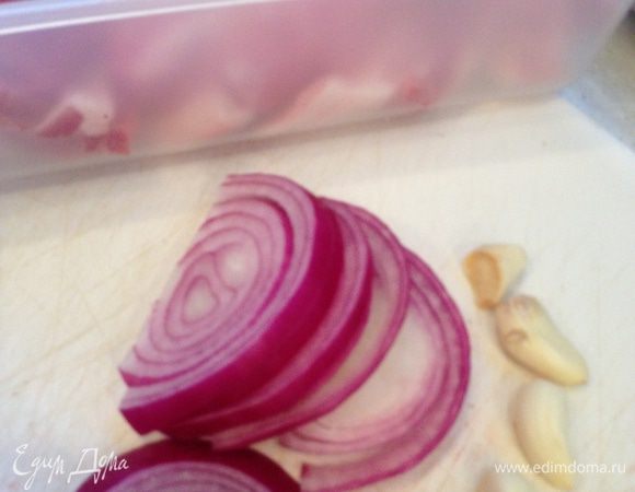 Если ребрышки не разрезаны, то нарезем их, затем режем лук полукольцами и натираем чеснок на мелкой терке