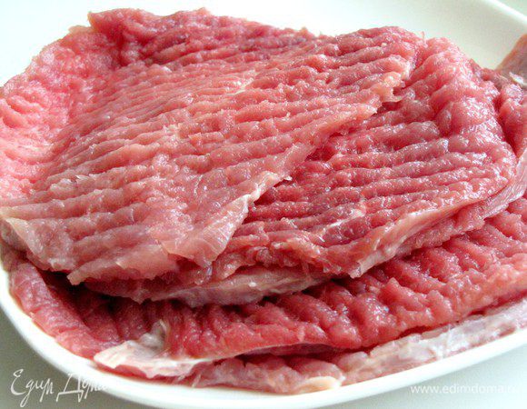 Говядину нарезать большими тонкими пластами, поперчить. Накрыть пленкой и отбить.