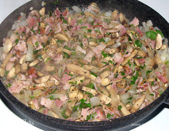 Добавить грибы, бекон, прованские травы, горсть петрушки, щепотку перца и соли,  сушеные грибы, растерев их пальцами. Все вместе обжарить.