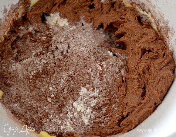 По-прежнему используя электромиксер, ввести порциями в масляную смесь муку с какао. 