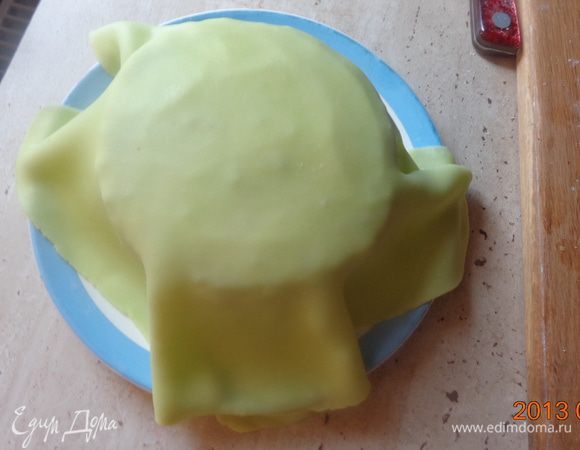 Верхний корж просто обтянуть зеленой мастикой и тщательно разгладить поверхность.
 Чтобы мастика хорошо "срослась" с основой, поставить все ярусы в холодильник хотя бы на полчаса. Можно сразу собрать все три яруса и охладить их вместе.