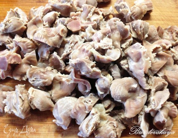В кастрюлю налить около 2 литров воды, нарезать по вкусу куриные желудочки и довести до кипения. Первый бульон слить, желудочки промыть. Затем вернуть их в кастрюлю, залить водой и варить  не менее 1 часа. 