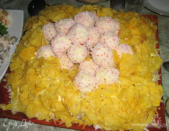 сырные шарики обвалять в крошках крабовых палочек и выложить в центр салата поверх чипсов