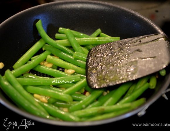 На сковороде разогреть оливковое масло, обжаривать чеснок 1 мин, затем добавить кедровые орешки 3 мин.
Воду слить с зеленой фасоли, фасоль положить в сковороду, посыпать солью и черным перцем. Обжаривать несколько минут.