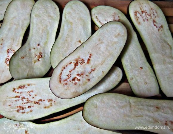 Баклажаны нарезать ломтиками толщиной 0,7-0,5 мм. Присыпать солью с обоих сторон, уложить в кастрюльку и оставить на 15-20 мин. После чего слить образовавшуюся жидкость, ополоснуть холодной водой, промокнуть ломтики баклажан бумажным полотенцем. При желании можно слегка обжарить ломтики на оливковом масле.