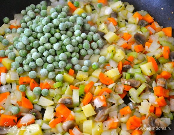 Добавить замороженный зеленый горошек и продолжать еще пару минут обжаривать.  