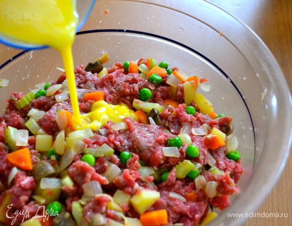 Разбить яйцо в стакане и взбить слегка вилкой. Половину яйца добавить в фарш с овощами. Еще раз все как следует перемешать. 
