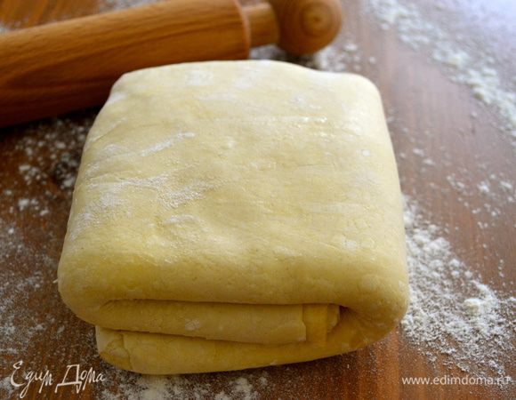 Рабочую поверхность стола присыпать мукой. Слоеное тесто раскатать в пласт размером примерно с кухонное полотенце. 