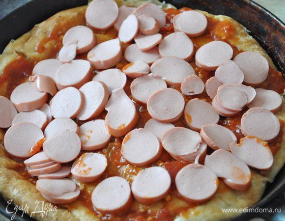 Сосиски порезать кружочками и разложить поверх соуса.