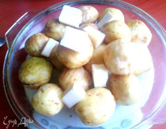 Мелкий картофель (крупный нарезать на четвертинки!) помыть и поскоблить молодую кожицу. Укладываем на тарелку или на крышку от стеклянной формы, как у меня...  Сверху хаотично кусочки маслица и соль по вкусу.