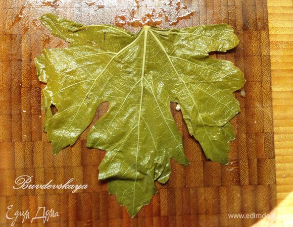 Виноградные листья аккуратно достать из банки, промыть под холодной водой и разобрать на отельные листочки. Аккуратно разложить листочки на рабочей поверхности матовой стороной вверх. Острым ножом удалить выступающий хвостик (черешок), основание листа с толстыми прожилками отбить деревянной  колотушкой или ложкой.
