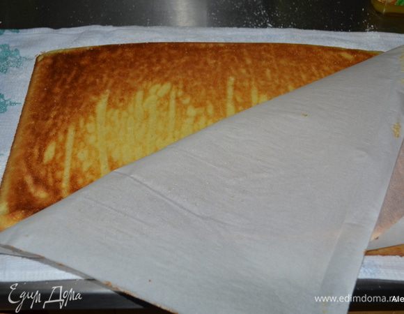 Приготовим полотенце, просеем на него сахарную пудру по размеру противня.
Готовый бисквит перевернем на полотенце. Снимем бумагу для выпечки.