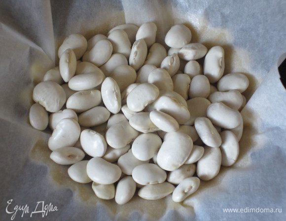 На тесто положить пекарскую бумагу и насыпать  фасоль. Выпекать в разогретой до 180 °С духовке 10 минут. 