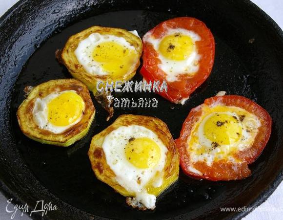 На отдельной сковороде (это для скорости) в небольшом количестве оливкового масла обжариваем колечки цукини и помидора. Колечки помидора добавляем чуть позже, потому что они готовятся значительно меньше по времени. Когда колечки зарумянятся с одной стороны, переворачиваем и в серединку каждого вбиваем перепелиное яйцо. Жарим до готовности яиц. Солим, перчим по вкусу.