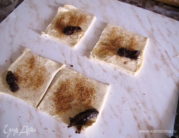Нарежьте тесто на квадратики, посыпьте смесью корицы и сахара, и положите на уголок ложечку пасты.