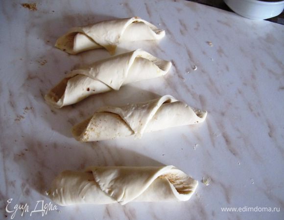 Скатайте в рулетики и смажьте чуть-чуть взбитым яйцом, которое мы приготовили для запеканки. Положите на противень.