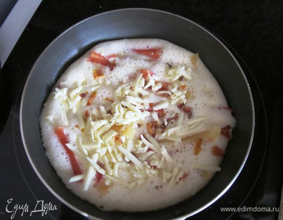 Нагреть сковороду, растопить маленький кусочек масла. Вылить омлетную смесь, выложить паприку, посыпать сыром, добавить сушеные томаты. Солить не надо, сыр отдаст свою соль и этого будет достаточно.