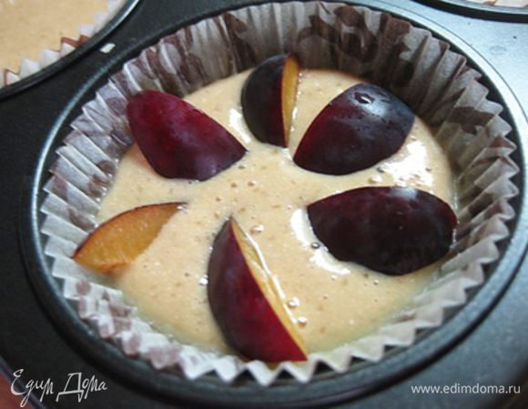 Формочки для кексов смазать маслом и заполнить тестом на 1/2.
Сливы очистить от косточек и нарезать дольками. Выложить поверх теста.