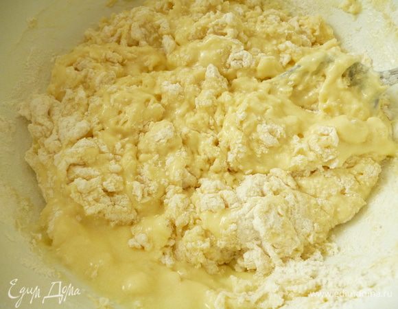 Постепенно добавить просеянную муку.Сначала перемешать с помощью ложки