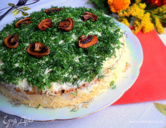 Также переслоить все пласты бисквита. Верх и бока смазать сырным кремом. Бока обсыпать тертым сыром, верх – мелко нарезанной зеленью (укроп, петрушка). Украсить поджаренными пластинками грибов. Поставить в холодильник охлаждаться на 1-2 часа.